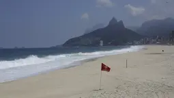 Bendera peringatan merah menghiasi hamparan pantai Arpoador yang ditutup karena diberlakukannya kembali pembatasan pandemi COVID-19 di Rio de Janeiro, Brasil, Sabtu (20/3/2021). Rio de Janeiro menutup pantai-pantainya yang terkenal untuk menekan angka kasus COVID-19. (AP Photo/Bruna Prado)