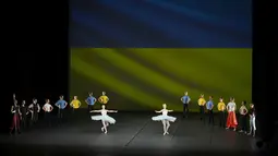 Penari Ukraina dari Balet Kota Kiev tampil di depan bendera Ukraina yang diproyeksikan ke layar di Theatre de Chatelet, di Paris (8/3/2022). Pertunjukan ini sebagai bagian dari acara malam untuk mendukung Ukraina setelah invasi Rusia. (AP Photo/Thibault Camus)