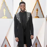 Aktor Chadwick Boseman berpose saat menghadiri Academy Awards ke-90 di Hollywood, California (4/3). Jas berhias sulaman mirip dengan busana yang dipakai ketika berperan sebagai T'Challa alias Black Panther. (Frazer Harrison / Getty Images / AFP)