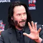 Aktor Keanu Reeves menunjukkan telapak tangannya yang masih berlumuran semen di halaman depan TCL Chinese Theatre, Los Angeles, Selasa (14/5/2019). Aktor 54 tahun itu mendapat penghargaan membuat cetakan tangan dan kaki untuk merayakan keberhasilan karirnya dalam film. (VALERIE MACON / AFP)