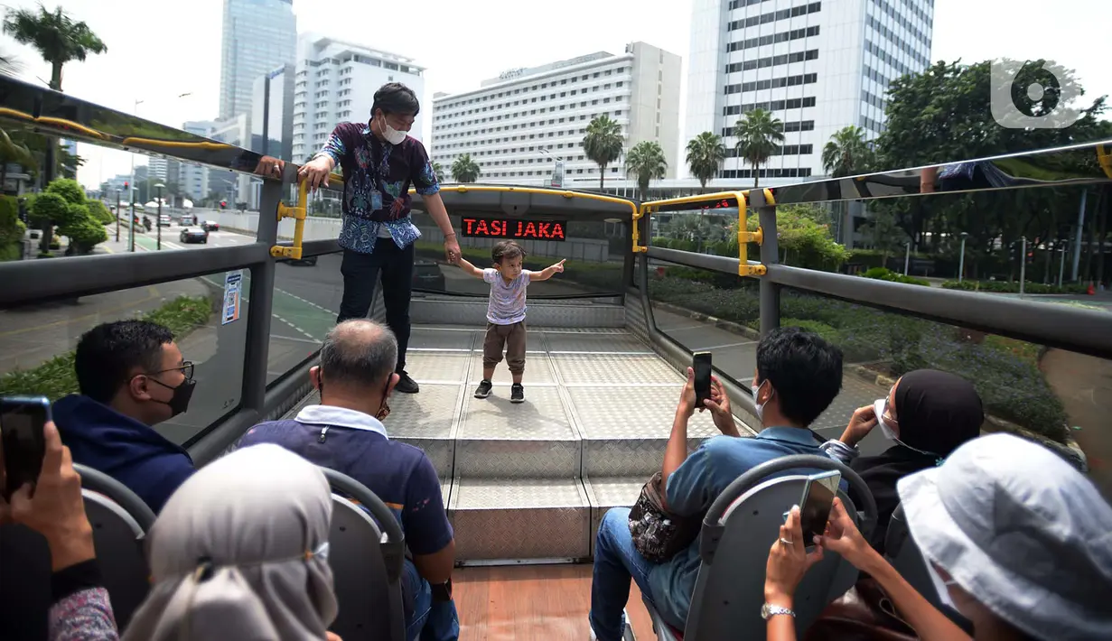 <p>Petugas memandu warga saat naik bus tingkat Transjakarta dengan atap terbuka di Jakarta, Selasa (10/5/2022). Selama libur Lebaran, bus wisata tersebut melayani warga menuju berbagai rute destinasi wisata Ibu Kota. (merdeka.com/Imam Buhori)</p>