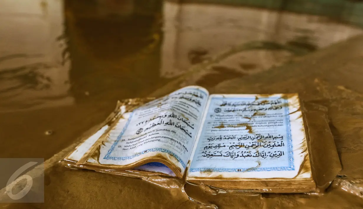 Sebuah kitab suci Al Qur'an dilumuri air lumpur usai banjir menggenangi masjid komplek Pondok Gede Permai, Bekasi, Jumat (22/4). Banjir di perumahan tersebut merendam lebih dari 500 rumah yang dihuni ribuan warga. (Liputan6.com/Fery Pradolo)