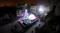Suasana perayaan malam Natal di kawasan Al-Hamidiyah yang dikelilingi reruntuhan bangunan kota tua Homs, Suriah, (24/12). (REUTERS/Omar Sanadiki)