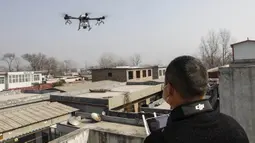 Seorang warga mengoperasikan drone yang membawa cairan desinfektan yang akan disemprotkan ke sebuah desa di Pingdingshan, Provinsi Henan, China (31/1/2020).  Cara ini digunakan untuk mencegah sekaligus mematikan partikel-partikel virus corona yang menyebar di setiap sudut daerah. (AFP Photo/Str)