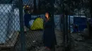 Seorang wanita imigran berbicara di telepon genggamnya di luar kamp pengungsi di pulau Samos, Yunani (13/11/2019). Ribuan imigran berjuang untuk menemukan ruang di perbukitan di atas kota, membuat rumah sementara dari bahan bangunan apa pun yang dapat mereka temukan. (AFP Photo/Angelos Tzortzinis)
