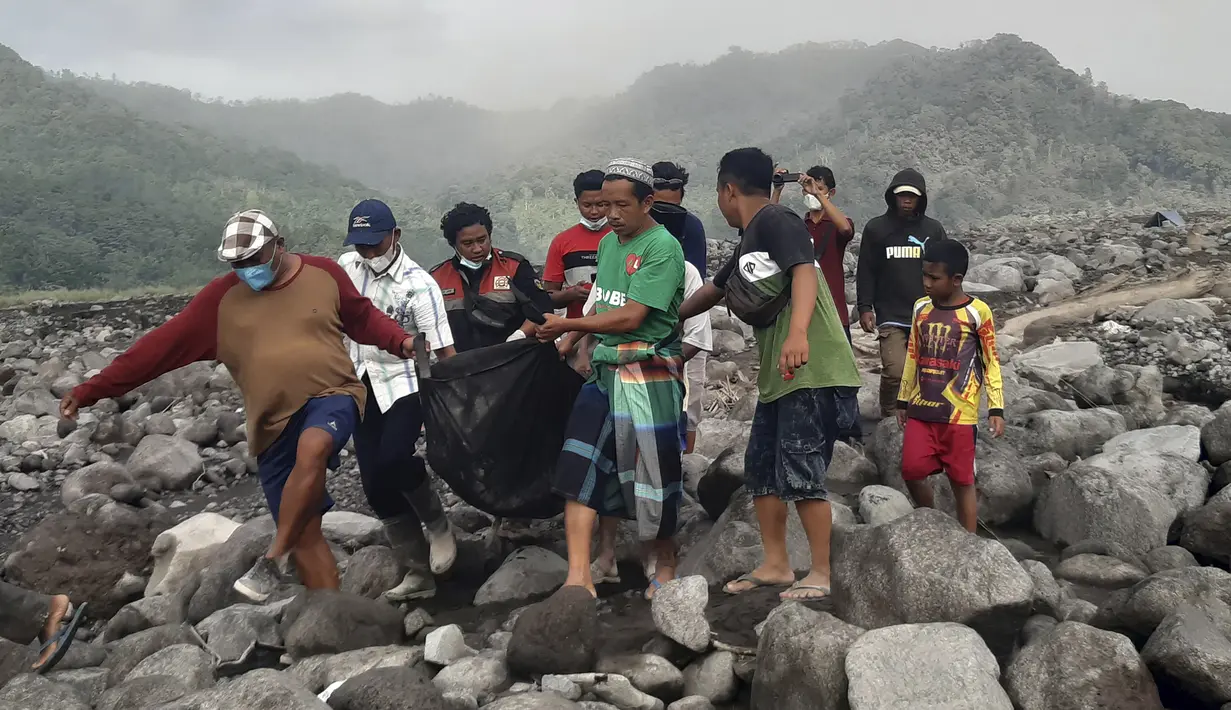 Tim penyelamat dan warga membawa kantong jenazah berisi jenazah korban letusan Gunung Semeru, di Desa Candi Puro, Lumajang, Jawa Timur, Selasa (7/12/2021). (AP Photo/Rokhmad)