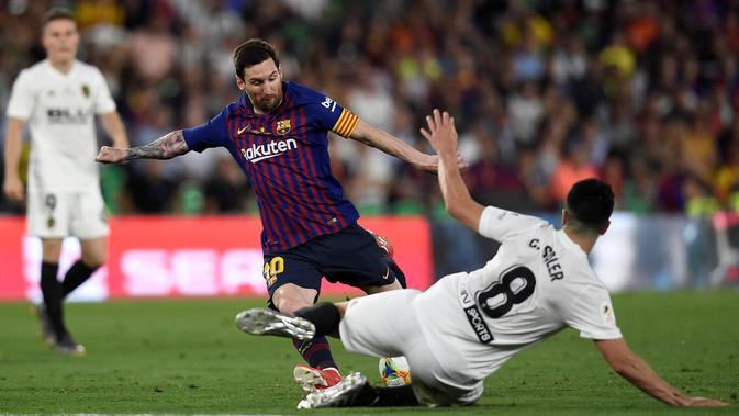 Gelandang Valencia Carlos Soler mencoba menghalangi laju Lionel Messi pada duel Barcelona versus Valencia pada final Copa del Rey 2019 di Stadion Benito Villamarín, Sevilla, Minggu (26/5/2019) dini hari. (AFP/Pau Barrena)