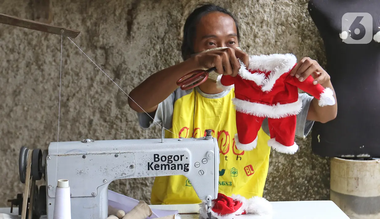 Fredi Lugina Priadi (39) menyelesaikan kostum santa claus untuk kucing di rumah industri di Desa Jampang, Kabupaten Bogor, Selasa (8/12/2020). Fredi merancang kostum unik untuk kucing seperti baju dokter atau superhero dengan harga dari Rp38 ribu hingga Rp1,5 juta. (Liputan6.com/Herman Zakharia)