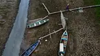 Seorang warga berjalan di samping perahu di hamparan Sungai Solimoes yang kering, akibat suhu tinggi yang melanda wilayah kota Manaquiri, di daerah pedesaan negara bagian Amazonas, Brasil, Sabtu, 21 Oktober 2023. (AP Photo/Edmar Barros)