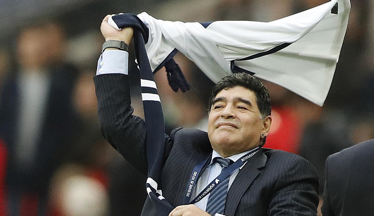 Diego Armando Maradona mengibarkan jersey Tottenham Hotspur saat mengyaksikan laga Premier Leagu antara Tottenham melawan Liverpool di Wembley Stadium, London, (22/10/2017). (AP/Frank Augstein)
