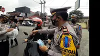 Petugas Polres Tasikmalaya, tengah memberikan reward helm bagi pengguna roda yang patuh menggunakan masker dan bersurat kendaraan lengkap, namun tidak berhelm, saat hari pertama operasi lodaya 2021. (Liputan6.com/Jayadi Supriadin)