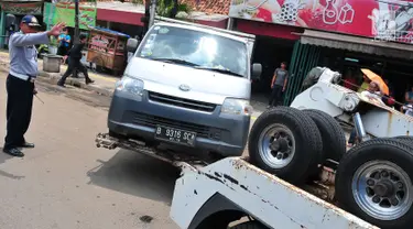 Petugas Dinas Perhubungan DKI Jakarta menderek mobil yang parkir di bahu jalan di kawasan Jatinegara, Jakarta, Senin (2/10). Razia parkir liar dilakukan untuk menertibkan kawasan tersebut. (Liputan6.com/Helmi Afandi)