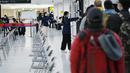Seorang staf mengarahkan penumpang untuk duduk dan menunggu giliran selama proses karantina pencegahan virus corona setelah mendarat di Bandara Internasional Narita di Narita, timur Tokyo, Jepang (2/12/2021). (AP Photo/Hiro Komae)