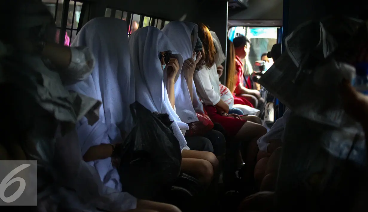 Sejumlah WNA menaiki mobil usai diamankan petugas di Direktorat Jenderal Imigrasi, Jakarta, Minggu (1/1). Dalam oprasi tersebut ditemukan sejumlah barang bukti, seperti paspor, uang tunai, alat kontrasepsi, dan pakaian dalam. (Liputan6.com/Faizal Fanani) 