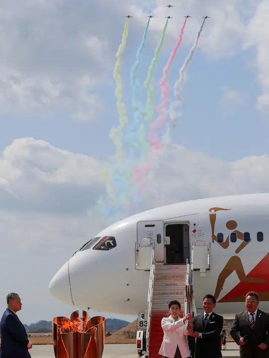 Jet Kawasaki T-4 dari tim Blue Impulse Pasukan Bela Diri Udara Jepang membentuk simbol olimpiade saat upacara kedatangan obor di Lanud Matsushima, Prefektur Miyagi, Jumat (20/3/2020).  Jepang bersikeras menyelenggarakan Olimpiade 2020 tepat waktu di tengah ancaman Covid- 19.  (STR/JIJI PRESS/AFP)