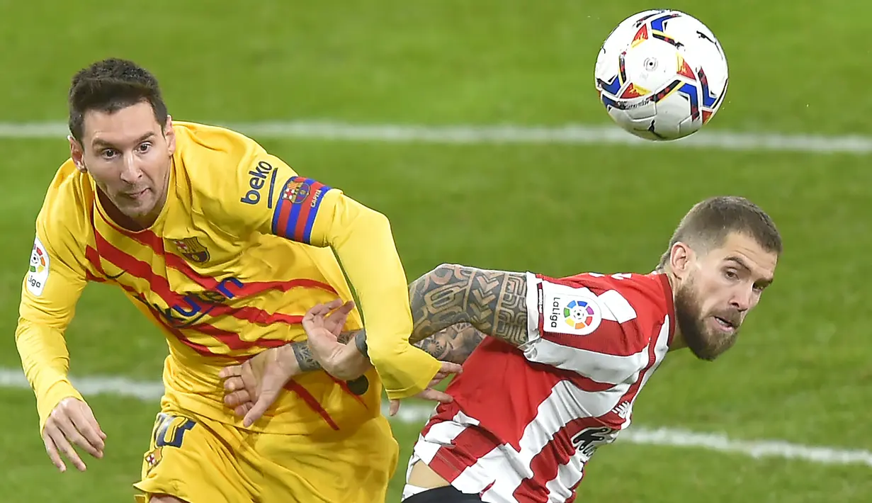 Striker Barcelona, Lionel Messi (kiri) berebut bola dengan bek Athletic Bilbao, Inigo Martinez dalam laga lanjutan Liga Spanyol 2020/21 di San Mames Stadium, Bilbao, Rabu (6/1/2021). Barcelona menang 3-2 atas Athletic Bilbao. (AFP/Ander Gillenea)