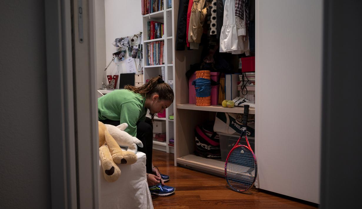 Vittoria Oliveri memakai sepatu sebelum bermain tenis dengan Carola Pessina di atap rumah mereka selama lockdown COVID-19 di Finale Ligure, Italia (19/4/2020). Setiap hari Carola, 11, dan Vittoria, 13, bermain tenis dari satu atap ke atap lain di rumah mereka untuk berlatih. (AFP/Marco Bertorello)