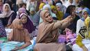 Seorang perempuan berswafoto sebelum sholat Idul Adha di sebuah jalan di Jakarta, Indonesia, Kamis, 29 Juni 2023. (AP Photo/Tatan Syuflana)