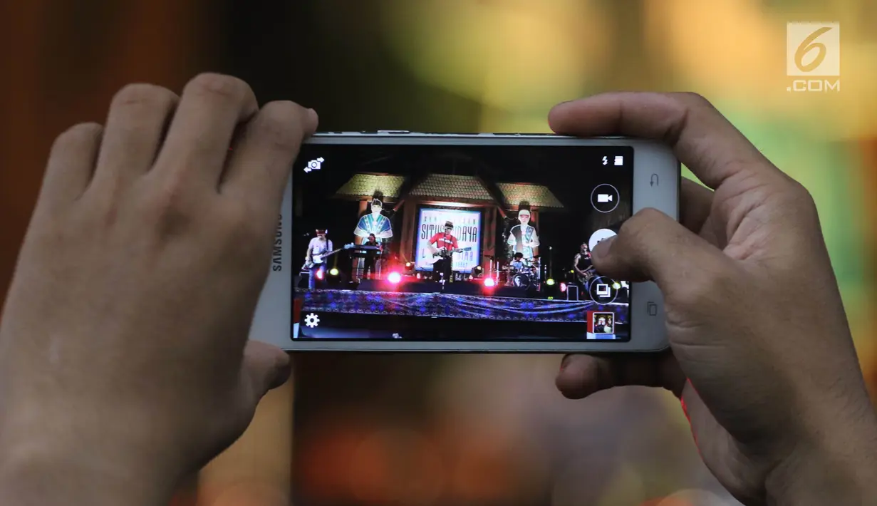 Penonton mengambil gambar dengan ponsel saat menonton Seri Konser Situs Budaya Iwan Fals dan Band di Panggung Kita, Depok, Sabtu (3/3). Konser Situs Budaya ini mengangkat budaya dari NTB Kerajaan Lombok dan Bima. (Liputan6.com/Arya Manggala)