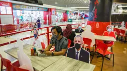Pengunjung menikmati makanan di meja yang diberi pembatas banner bergambar karakter kepala negara di Restoran Hulu Hulu, Mall Kuningan City, Jakarta, Senin (1/3/2021). Banner bergambar tersebut berguna untuk pembatas bagi pengunjung yang makan di tempat saat pandemi. (Liputan6.com/Faizal Fanani)