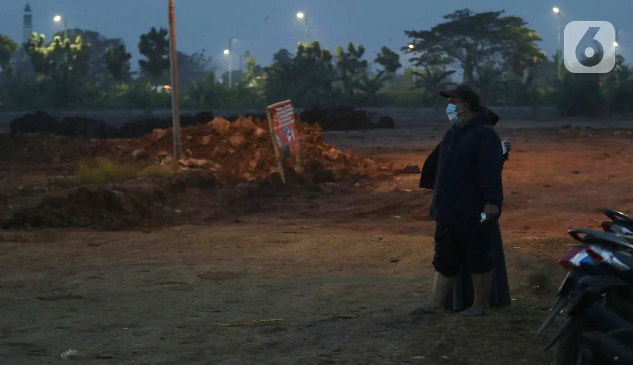 Kerabat menyaksikan pemakaman jenazah dengan protokol Covid-19 dari zona aman di TPU Rorotan, Jakarta, Rabu (23/6/2021). Gubernur Provinsi DKI Jakarta Anies Baswedan mengatakan, hingga Rabu (23/6) 900 jenazah dimakamkam dengan protokol Covid-19 di TPU Rorotan.  (Lipiutan6.com/Helmi Fithriansyah)