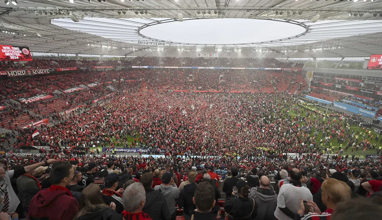 Suporter Bayer Leverkusen memadati lapangan pertandingan untuk merayakan keberhasilan timnya memastikan gelar juara Liga Jerman 2023/2024 setelah mengalahkan Werder Bremen di BayArena, Leverkusen, Jerman, Senin (15/04/2024) WIB. (AP Photo/DPA/David Inderlied)
