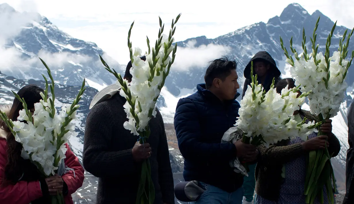 Orang-orang memegang bunga untuk persembahan ritual Pachamama atau Ibu Bumi di gunung La Cumbre, pinggiran La Paz, Bolivia, Rabu (1/8). Bulan Agustus adalah saat dimana melakukan persembahan menghormati dewi bumi dan meminta keberuntungan (AP/Juan Karita)