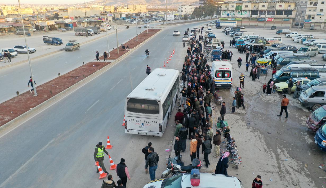 Foto udara menunjukkan pengungsi Suriah yang tinggal di Turki menunggu untuk naik bus melalui penyeberangan perbatasan Bab al-Hawa utara, pada 17 Februari 2023, saat mereka kembali ke Suriah setelah gempa bumi yang mematikan. Turki minggu ini mengizinkan warga Suriah di bawah perlindungannya yang memegang kartu identitas dari salah satu provinsi yang dilanda gempa untuk pergi antara tiga dan enam bulan. (AFP/Omar Haj Kadour)