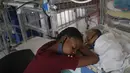 Seorang ibu beristirahat dekat anaknya yang baru lahir di Rumah Sakit Anak Saint Damien Port-au-Prince, Haiti, Minggu (24/10/2021). Dilanda krisis, rumah sakit pediatri utama ibu kota hanya memiliki sisa bahan bakar dalam 3 hari untuk menjalankan ventilator dan peralatan medis. (AP/Matias Delacroix)