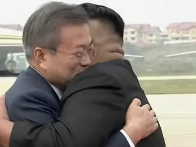 Presiden Korea Selatan, Moon Jae-in (kiri) memeluk pemimpin Korea Utara, Kim Jong-un setibanya di Pyongyang, Selasa (18/8). Kedatangan Moon Jae-in ke negara tersebut adalah untuk pertemuan ketiga dengan Kim Jong-un. (Korea Broadcasting System via AP)