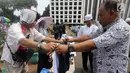 Calon pembeli melihat kaos #2019GantiPresiden di halaman Masjid Istiqlal, Jakarta, Jumat (10/8). Pedagang menjual kaos lengan panjang dan pendek berwarna putih, hitam, biru dan merah. (Liputan6.com/Fery Pradolo)