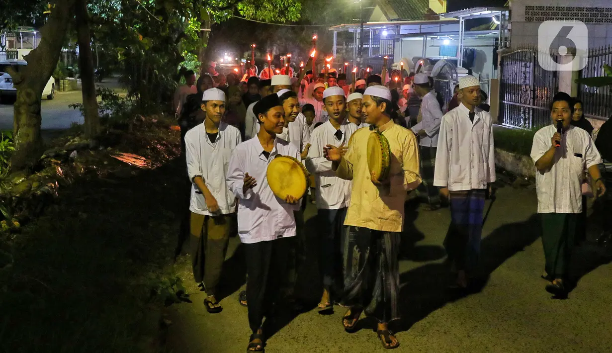 Umat muslim memainkan rebana saat yang lainnya membawa obor sambil berkeliling kampung di kawasan Kota Tangerang, Banten, Jumat (29/7/2022) malam. Pawai obor tersebut digelar untuk menyambut malam pergantian Tahun Baru Islam atau 1 Muharam 1444 H. (Liputan6.com/Angga Yuniar)