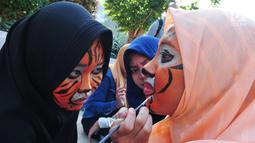 Peserta aksi dari forum harimaukita berdandan sebelum melakukan aksi teatrikal di Bundaran HI, Jakarta, Minggu (30/7). Acara ini diharapkan mampu meningkatkan minat masyarakat untuk terlibat dalam melestarikan habitat harimau.  (Liputan6.com/Helmi Afandi)