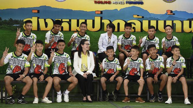12 anak laki-laki dan pelatih sepak bola mereka, yang diselamatkan dari gua banjir di Thailand tampil ke muka publik untuk pertama kalinya di Chiang Rai, Rabu (18/7). Mereka memasuki ruang konferensi pers dengan memakai seragam. (LILLIAN SUWANRUMPHA /AFP)