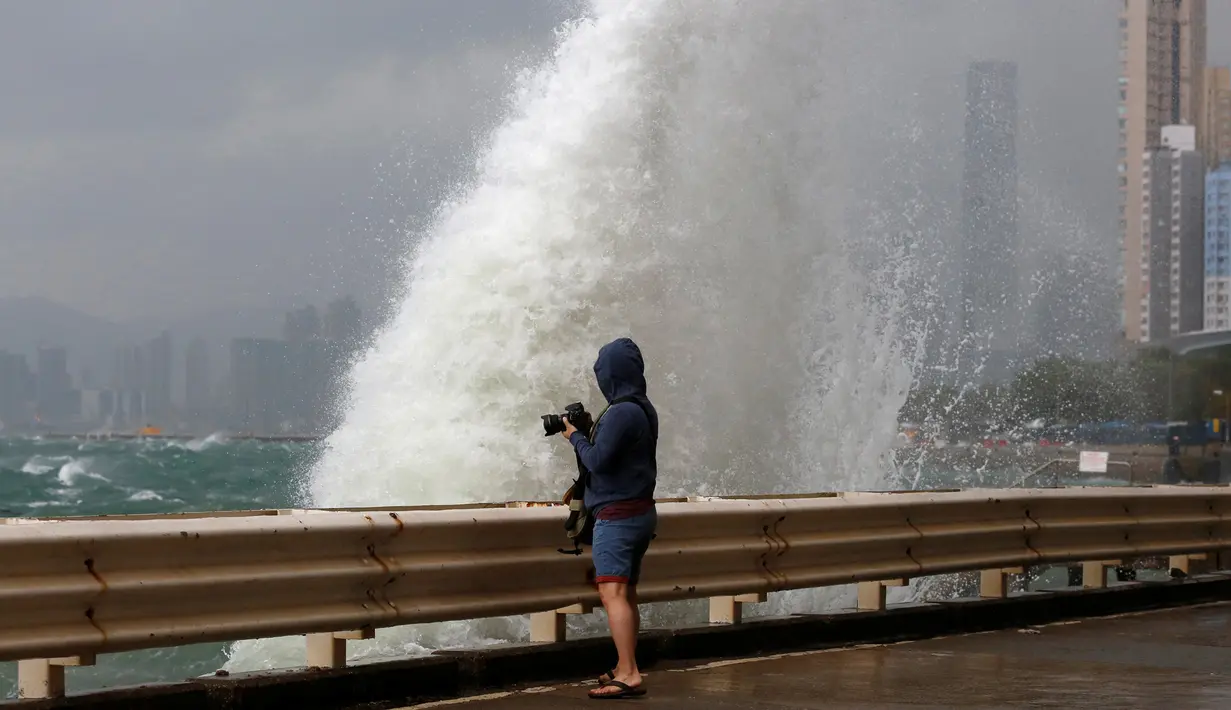 Warga mengabadikan ombak besar dengan kameranya di pesisir Hong Kong, China, Jumat (21/10). Akibat terjangan angin berkecepatan 160 kilometer per jam itu, sedikitnya 700 penerbangan di Hongkong ditunda atau dibatalkan. (REUTERS/Bobby Yip)