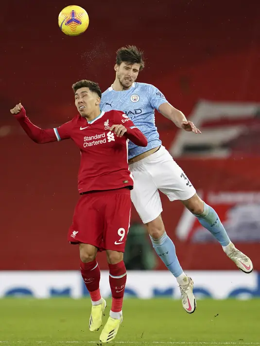 Striker Liverpool, Roberto Firmino berebut bola udara dengan bek Manchester City, Ruben Dias  pada pertandingan lanjutan Liga Inggris di Stadion Anfield, Inggris, Senin (8/2/2021).  City menang telak atas Liverpool 4-1. (AP photo/Jon Super, Pool)