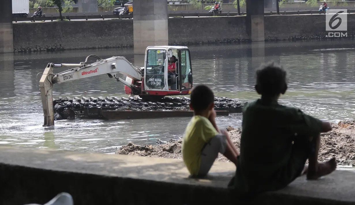 Dua bocah melihat proses pengerukan Waduk Grogol, Jakarta, Senin (9/4). Pengerukan dilakukan untuk mengatasi permasalahan banjir di Ibu Kota. (Liputan6.com/Arya Manggala)