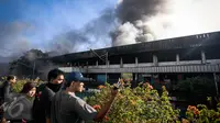 Sejumlah warga menonton kebakaran yang melahap pusat perbelanjaan Blok III Pasar Senen, Jakarta Pusat, Kamis (19/1). Kobaran api tampak menimbulkan asap pekat yang membumbung ke angkasa. (Liputan6.com/Faizal Fanani)