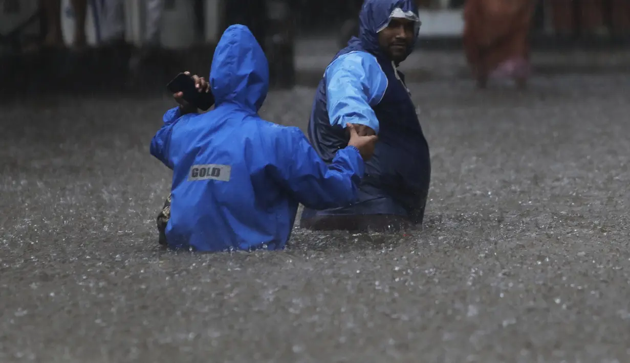Orang-orang menyeberang jalan melintasi banjir saat hujan lebat di Mumbai, India, Rabu, (5/8/2020). Musim hujan India berlangsung dari Juni hingga September. (AP Photo/Rajanish Kakade)
