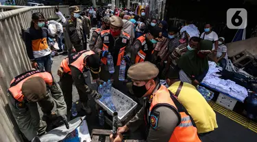 Aparat gabungan mengangkut dagangan pedagang yang berjualan di trotoar di kawasan Tanah Abang, Jakarta, Minggu (2/5/2021). Selain merazia barang dagangan pedagang, aparat gabungan juga menegur warga yang tidak menerapkan protokol kesehatan. (Liputan6.com/Johan Tallo)