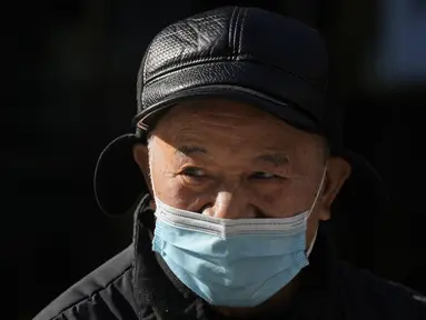 Seorang pria mendongak sambil mengenakan topeng di jalan Beijing, China, Selasa (14/12/2021). Media pemerintah China mengatakan Senin, 13 Desember 2021, kasus pertama varian omicron COVID-19 telah terdeteksi di daratan negara di kota Tianjin di sebelah timur Beijing. (AP Photo/Ng Han Guan)
