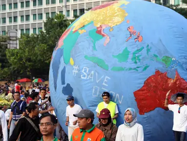 Replika bola dunia berukuran besar digelindingkan di sekitar kawasan Bundaran Hotel Indonesia, Jakarta, Minggu (16/9). Acara ini bagian dari peringatan Hari Ozon Sedunia yang jatuhnya setiap tanggal 16 September. (Liputan6.com/Helmi Fithriansyah)
