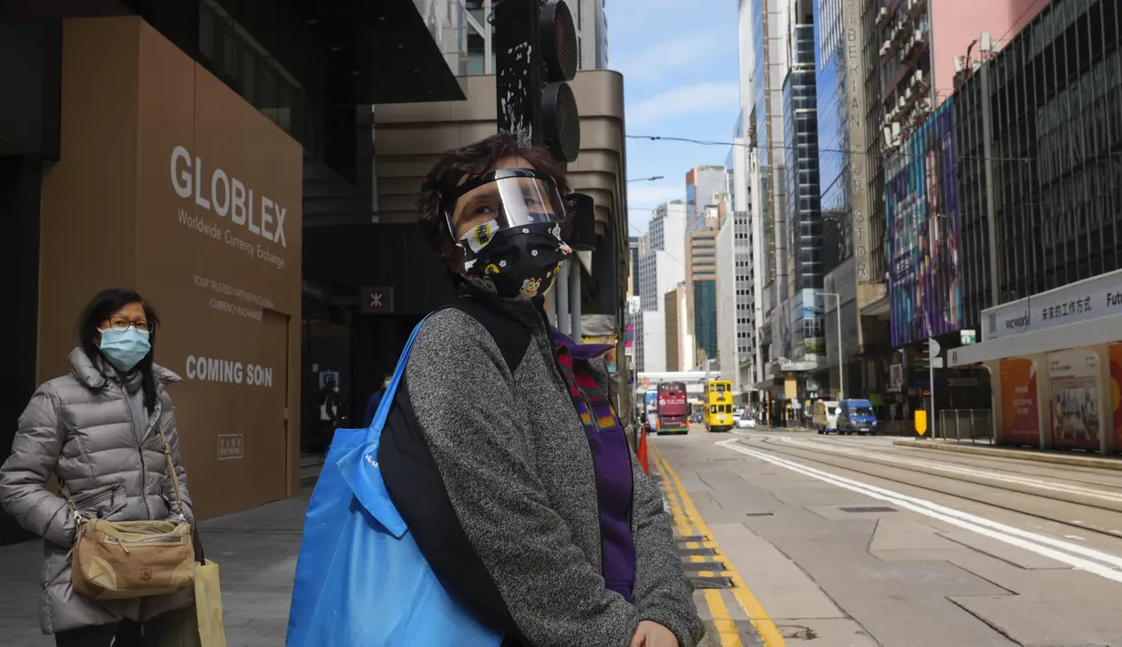 Orang-orang yang memakai masker berjalan di jalan pusat kota di Hong Kong, 23 Februari 2022. Warga Hong Kong menjadi semakin kesal dengan desakan pemerintah untuk tetap berpegang pada strategi "nol-COVID" ketika kota itu mencatat rekor jumlah kasus baru lainnya pada hari Rabu. (AP Photo/Vincent Yu)