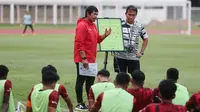 Pelatih kepala Timnas Indonesia U-19, Indra Sjafri (kiri) didampingi asisten pelatih, Bima Sakti memberi pengarahan kepada para pemainnya dalam rangkaian pemusatan latihan Timnas Indonesia U-19 di Stadion Madya, Senayan, Jakarta, Senin (1/7/2024) sebagai persiapan menghadapi ajang Piala AFF U-19 2024 yang akan berlangsung pada 17 hingga 29 Juli 2024. (Bola.com/M Iqbal Ichsan)