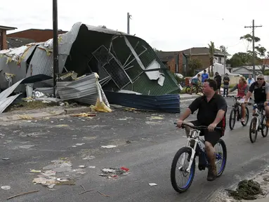 Warga bersepeda sambil mengamati kerusakan dari sebuah rumah akibat badai tornado yang langka di Kurnell pinggir Sydney, Rabu (16/12). Badai dengan hujan es disertai angin berkekuatan sampai 200 km per jam melanda kawasan tersebut. (REUTERS/Jason Reed)