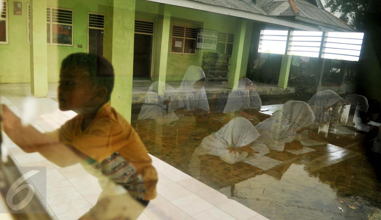 Siswa MI Mansyaul Huda mengikuti pelajaran di kelas yang terkena dampak abrasi pantai Muara Gembong, Bekasi, Selasa, (26/7). Tingkat abrasi yang tinggi menyebabkan sejumlah rumah dan sekolah terkikis dan terendam air laut. (Liputan6.com/Gempur M Surya)
