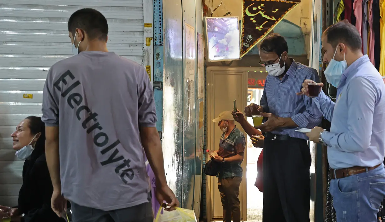 Pelanggan minum teh di luar kedai teh terkecil dan tertua yang terletak di gang Grand Bazaar di ibukota Iran, Teheran (20/9/2021).  Di sela-sela menuangkan segelas teh untuk pelanggannya, Kazem memberi tahu kisah seabad tentang Rumah Teh Haj Ali Darvish dengan bangga. (AFP/Atta Kenare)