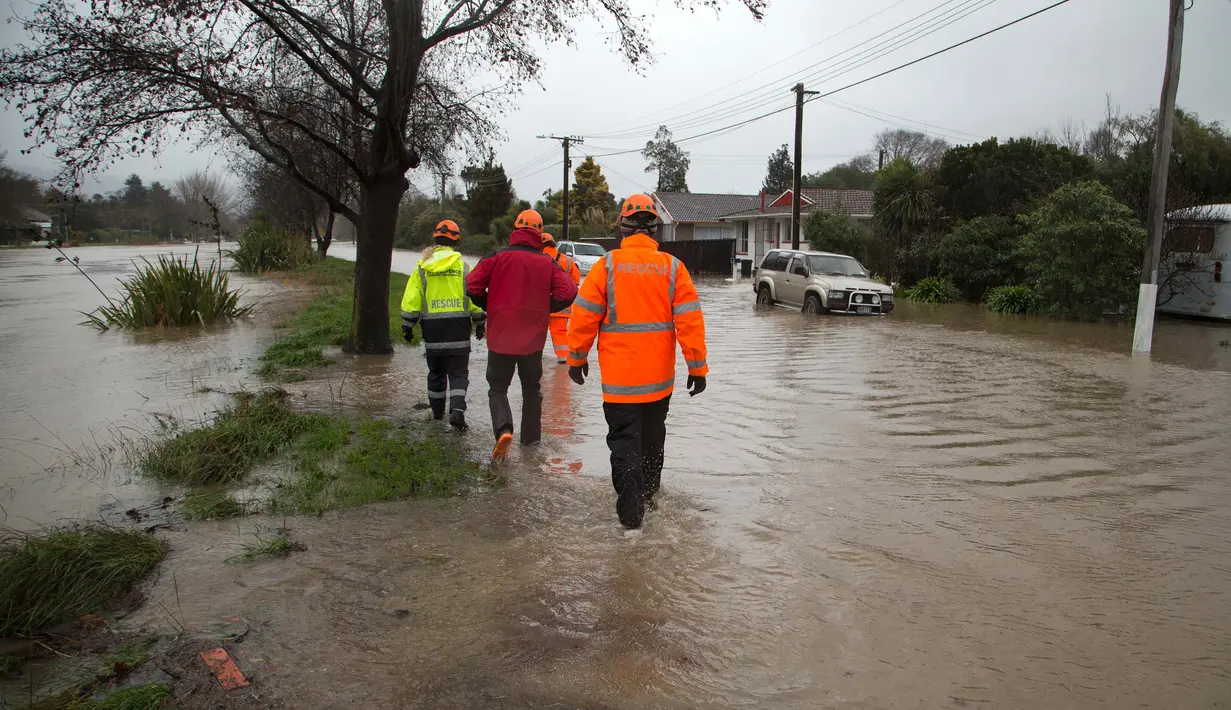 Petugas melintasi banjir untuk mengevakuasi pemilik rumah di Christchurch, Selandia Baru, Sabtu, (22/7). Dewan Kota Christchurch mengatakan keadaan darurat setelah Sungai Heathcote meluap akibat cuaca yan buruk. (AP Photo / Mark Baker)
