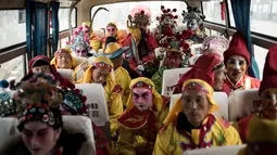 Penduduk desa mengenakan kostum tradisional berada di dalam bus untuk pergi menghadiri festival She Huo di Longxian, provinsi Shaanxi, Tiongkok (27/2). Festival ini juga sebagai perayaan untuk dewa tanah dan api. (AFP Photo/Fred Dufour)