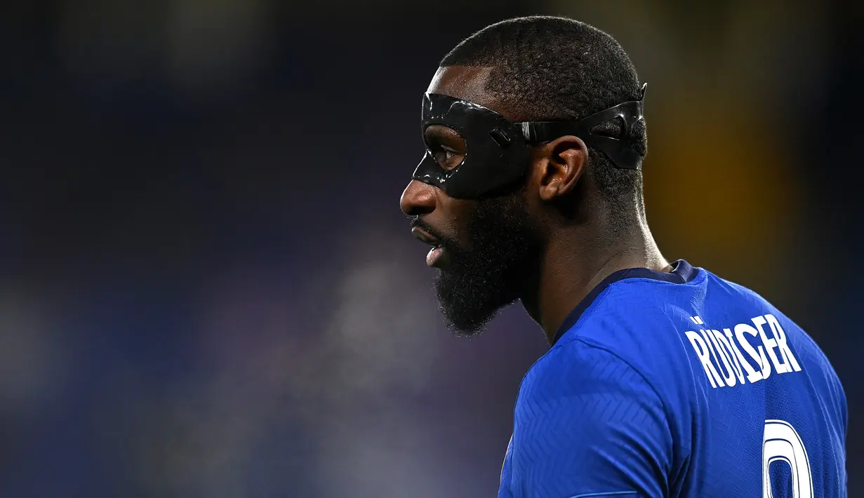 Antonio Rudiger. Bek tengah Jerman berusia 29 tahun yang yang baru saja bergabung dengan Real Madrid di awal musim 2022/2023 usai meninggalkan Chelsea yang telah dibela sejak 2017/2018 ini tercatat pernah mengenakan topeng saat membela The Blues akibat cedera pada 2021. Cedera didapat saat Chelsea berhadapan dengan tamunya Real Madrid pada leg pertama semifinal Liga Champions 2020/2021. Saat itu ia beradu kepala dengan bek Real Madrid Raphael Varane dalam situasi duel udara. (AFP/Glyn Kirk)